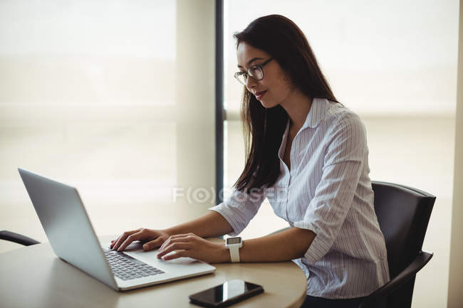 Businesswoman working on laptop in office — Stock Photo