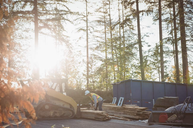 Construction worker loading timber on bulldozer at construction site — Stock Photo