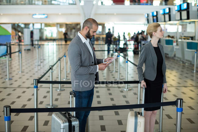 Ділові люди, які чекають черги на стійці реєстрації з багажем в терміналі аеропорту — стокове фото