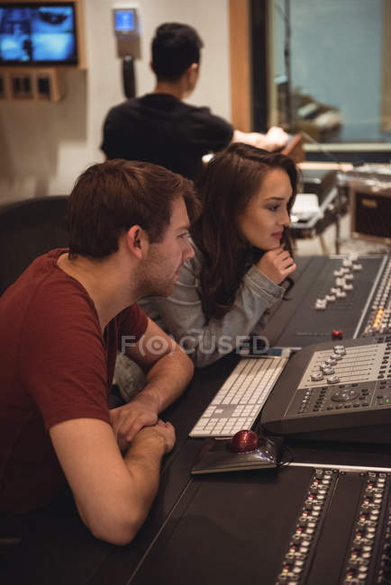 Задумчивые звукоинженеры, работающие над миксером в музыкальной студии — стоковое фото