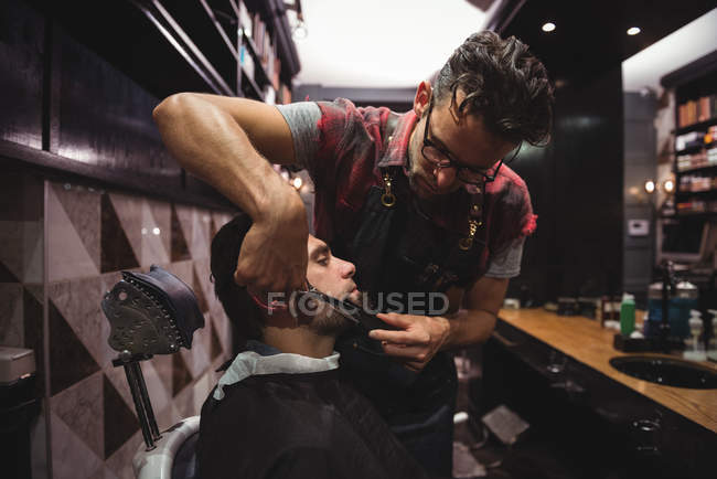 Customer getting beard trimmed with scissors in barber shop — Stock Photo