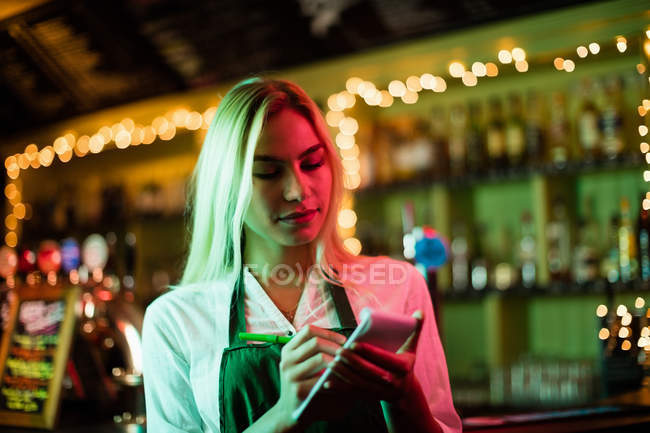 Официантка пишет заказ на блокнот в баре — стоковое фото