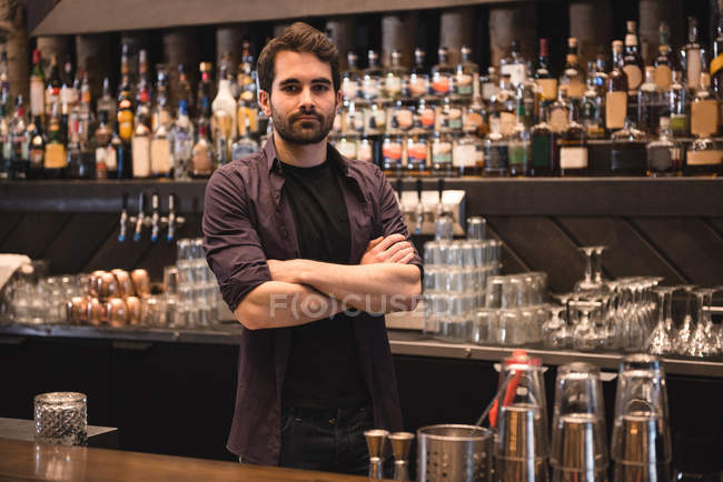 Retrato de un camarero confiado parado en el mostrador del bar - foto de stock