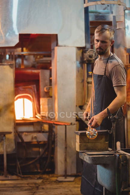 Glassblower shaping a glass on the blowpipe at glassblowing factory — Stock Photo