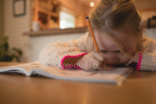 Внимательная девушка делает домашнее задание в гостиной на дому — стоковое фото