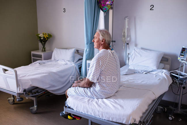 Thoughtful male senior patient sitting in the ward at hospital — Stock Photo