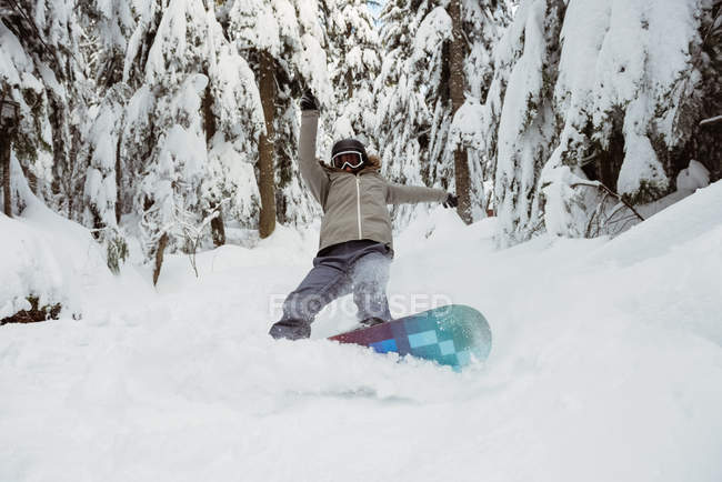 Woman snowboarding on snowy mountain slope — Stock Photo