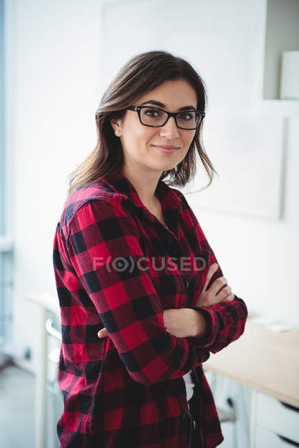 Portrait of smiling business executive standing with arms crossed in office — Stock Photo