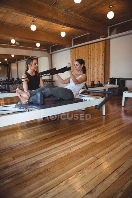 Coach aider une femme tout en pratiquant pilates dans un studio de fitness — Photo de stock