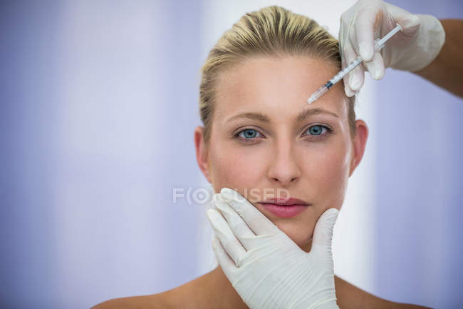 Close-up of female patient receiving botox injection on forehead — Stock Photo