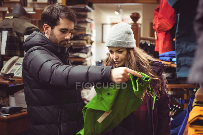 Pareja seleccionando ropa juntos en una tienda de ropa - foto de stock