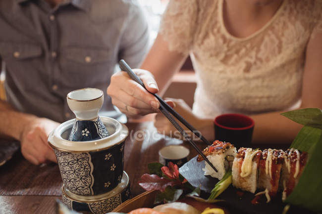 Seção intermediária de casal que tem sushi em restaurante — Fotografia de Stock
