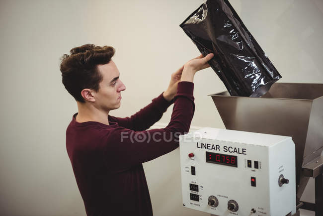 Man pouring coffee beans in weighing machine in coffee shop — Stock Photo