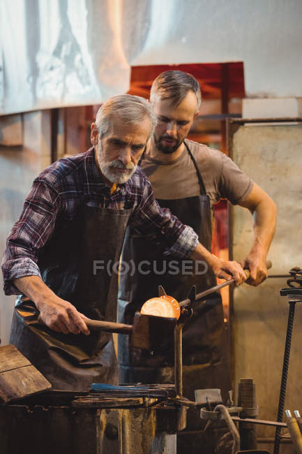 Team of glassblower forming and shaping a molten glass at glassblowing factory — Stock Photo