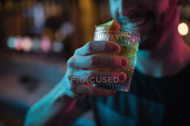 Uomo sorridente che beve cocktail nel bar — Foto stock