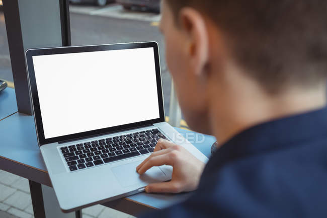 Male executive using laptop at counter in cafeteria — Stock Photo