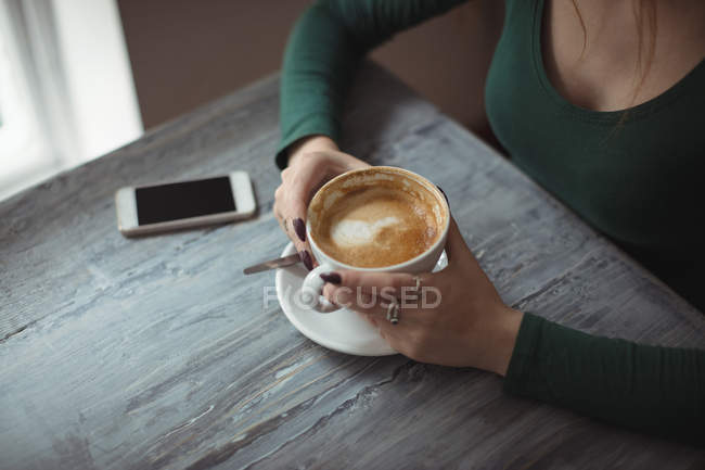 Vista ad alto angolo della donna che tiene in mano la tazza di caffè — Foto stock