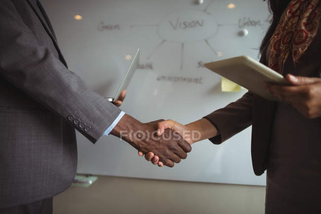 Средняя секция бизнесмена и коллеги пожимают друг другу руки в офисе — стоковое фото
