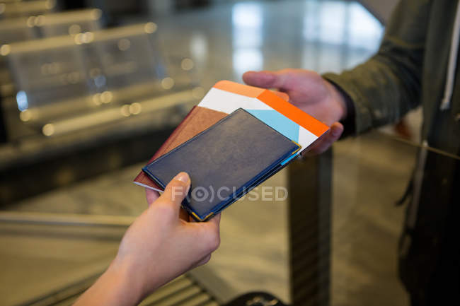 Mãos do funcionário do check-in da companhia aérea que entrega passaportes aos passageiros no balcão de check-in do aeroporto — Fotografia de Stock