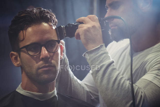 Client getting hair trimmed with trimmer in barber shop — Stock Photo
