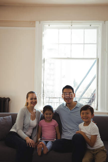 Porträt lächelnder Eltern und Kinder auf Sofa mit digitalem Tablet im heimischen Wohnzimmer — Stockfoto