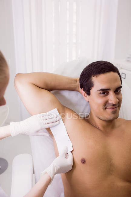 Médico encerando a pele do paciente masculino na clínica — Fotografia de Stock