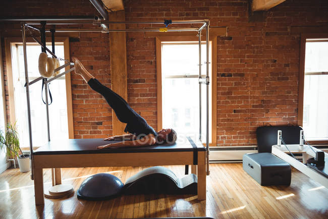 Side view of woman practicing pilates on fitness studio equipment — Stock Photo