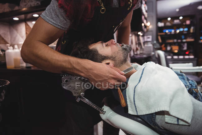 Cliente ottenere barba rasata con rasoio in negozio di barbiere — Foto stock