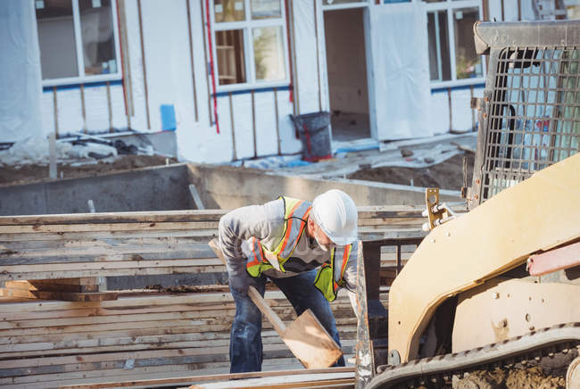 Trabalhador da construção que carrega madeira no bulldozer no canteiro de obras — Fotografia de Stock