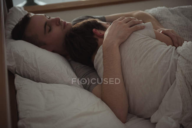 Gay coppia abbracciare mentre dormire su letto in camera da letto — Foto stock