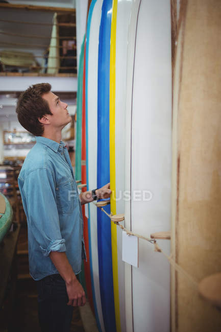 Чоловік дивиться на барвисті дошки для серфінгу в магазині — стокове фото