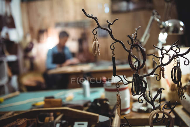 Various leather accessories hanging on hooks in workshop — Stock Photo