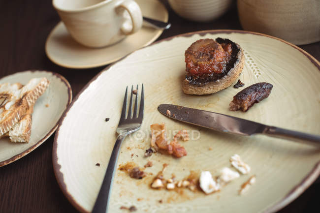 Gros plan sur les restes de petit déjeuner dans une assiette au café — Photo de stock