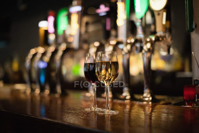 Copas de vino tinto y blanco en el mostrador de bar en el bar - foto de stock