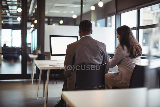 Geschäftsmann und ein Kollege, der im Büro am Computer arbeitet — Stockfoto