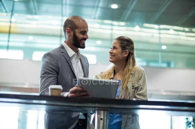 Coppia sorridente che interagisce con ciascuno o in sala d'attesa presso il terminal dell'aeroporto — Foto stock