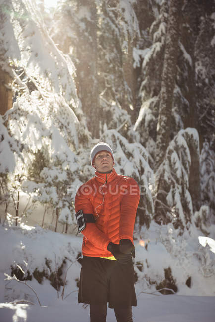 Hombre reflexivo estirando los brazos en el bosque durante el invierno - foto de stock