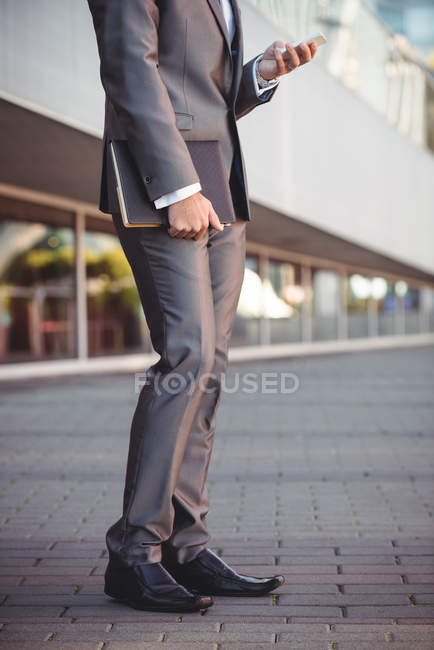 Low section of businessman using mobile phone near office building — Stock Photo