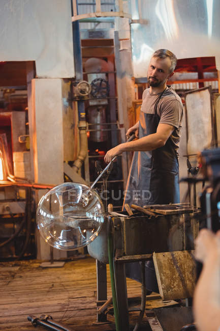 Soplador de vidrio dando forma a un vidrio en la tubería de soplado en la fábrica de soplado de vidrio - foto de stock