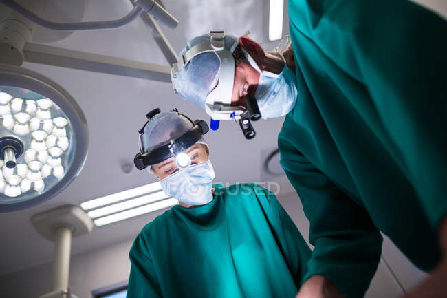 Cirurgiões vestindo lupas cirúrgicas durante a realização da operação no teatro de operação — Fotografia de Stock