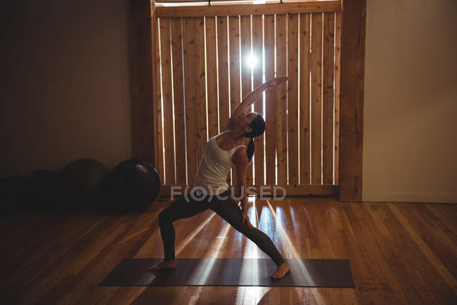 Mujer practicando yoga en gimnasio con retroiluminación - foto de stock
