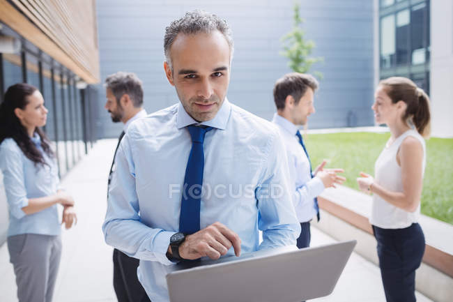 Homme d'affaires utilisant un ordinateur portable à l'extérieur du bâtiment de bureaux — Photo de stock