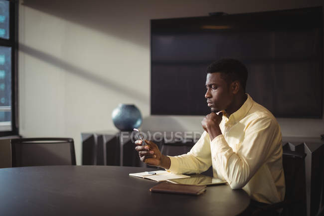 Uomo d'affari che utilizza il telefono cellulare in ufficio — Foto stock