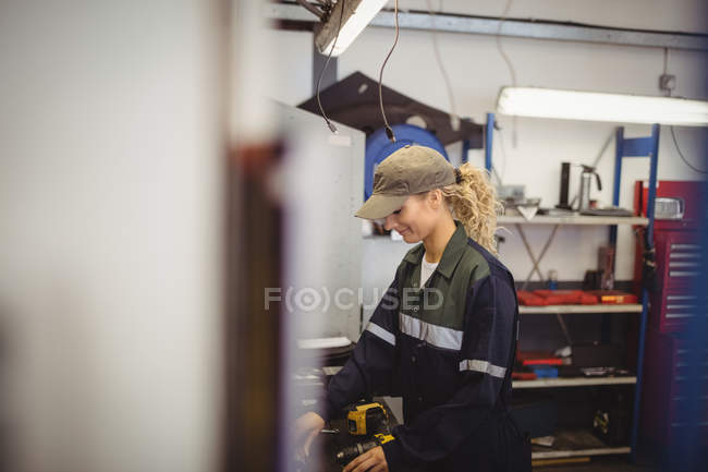 Женщина-механик проверяет детали автомобиля в ремонтном гараже — стоковое фото