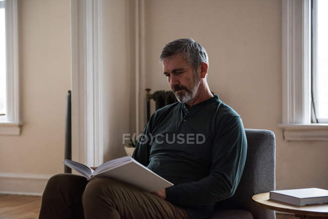 Man reading book in living room at home — Stock Photo