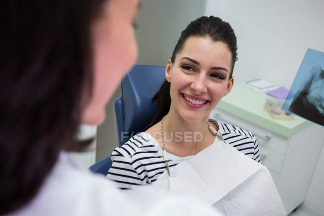 Жінка-пацієнтка посміхається, розмовляючи з лікарем у клініці — стокове фото