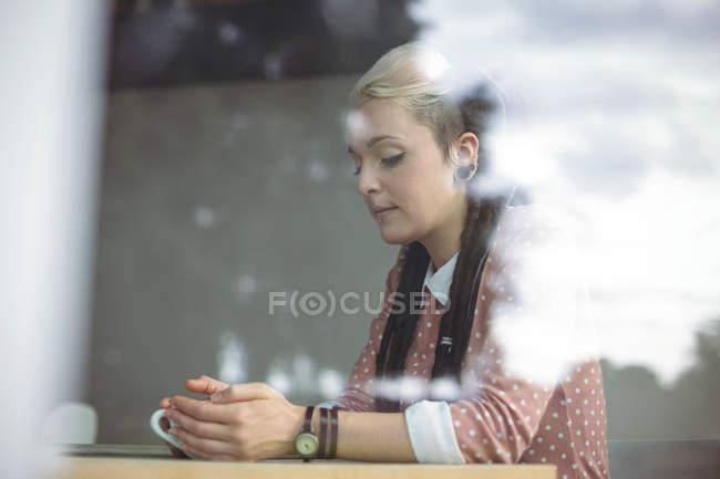 Задумчивая женщина пьет кофе в кафе — стоковое фото