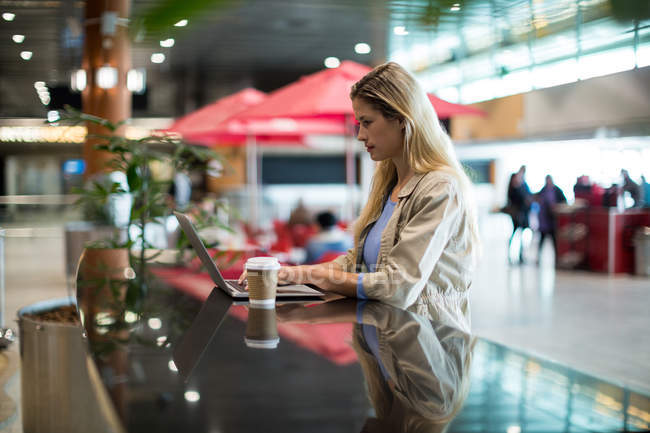 Mulher bonita usando laptop na área de espera no terminal do aeroporto — Fotografia de Stock