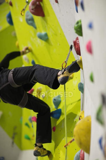 Homem praticando escalada na parede de escalada artificial no ginásio — Fotografia de Stock