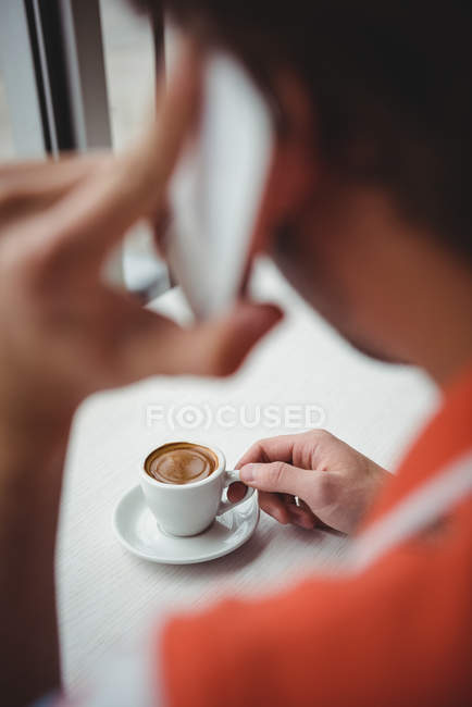 Homme parlant sur téléphone portable tout en prenant un café dans le café — Photo de stock